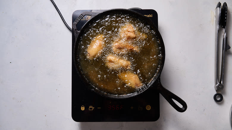 chicken frying in oil in cast iron skillet