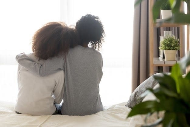 A woman embraces her daughter in her bedroom