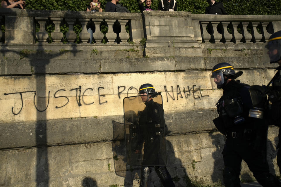 Police patrol as youths gather on Concorde square during a protest in Paris, France, Friday, June 30, 2023. French President Emmanuel Macron urged parents Friday to keep teenagers at home and proposed restrictions on social media to quell rioting spreading across France over the fatal police shooting of a 17-year-old driver. Writing on wall reads in French "Justice for Nahel" (AP Photo/Lewis Joly)