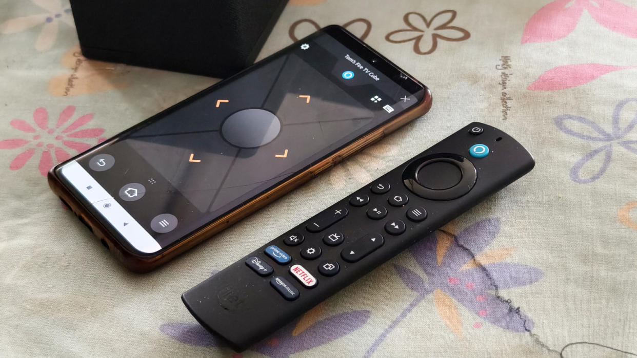  A smartphone with the Amazon Fire TV app next to the Alexa remote. 