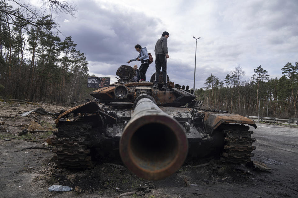 FILE - Local residents stand atop of a Russian tank damaged during fightings between Russian and Ukrainian forces in the outskirts of Kyiv, Ukraine, Monday, April 11, 2022. With Russia’s military failings in Ukraine mounting, no country is paying closer attention than China to how a smaller, outgunned force has badly bloodied what was thought to be one of the world’s strongest armies. (AP Photo/Evgeniy Maloletka, File)