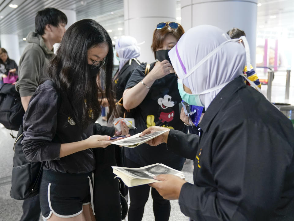 Health officials hand out information about the current coronavirus at Kuala Lumpur International Airport in Sepang, Malaysia, Tuesday, Jan. 21, 2020. Countries both in the Asia-Pacific and elsewhere have initiated body temperature checks at airports, railway stations and along highways in hopes of catching those at risk of carrying a new coronavirus that has sickened more than 200 people in China. (AP Photo/Vincent Thian)
