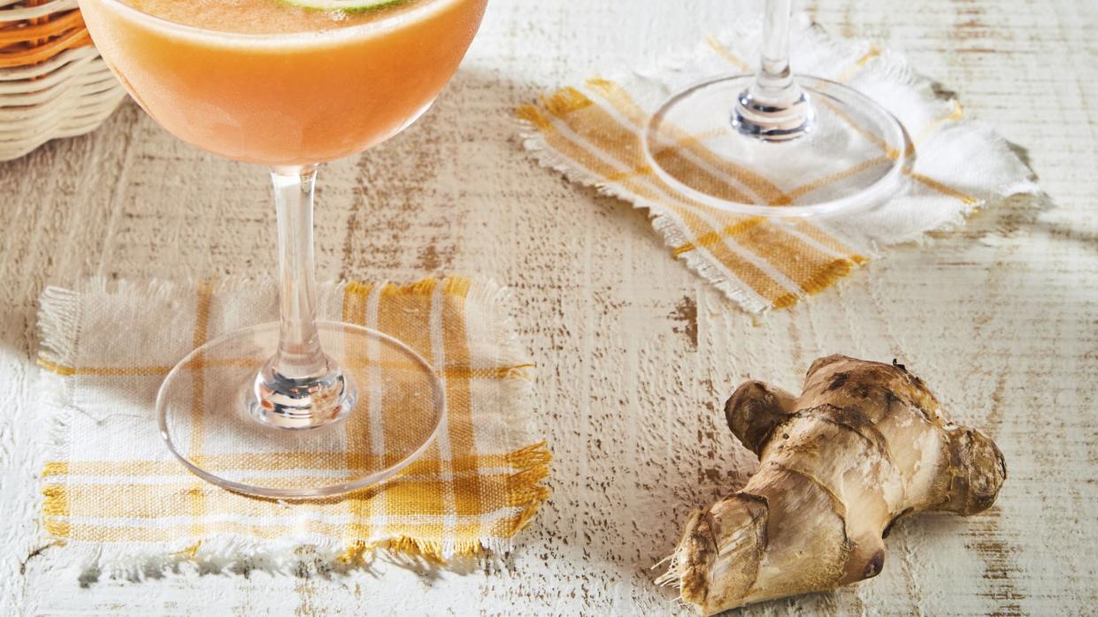 a couple of glasses with orange liquid and a slice of orange