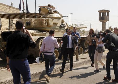 Al Jazeera television journalist Baher Mohamed (L) talks on the mobile as journalist Mohamed Fahmy (C) reaches out to shake hands with a TV journalist as they arrive outside Tora prison in Cairo, Egypt, July 30, 2015. REUTERS/Asmaa Waguih