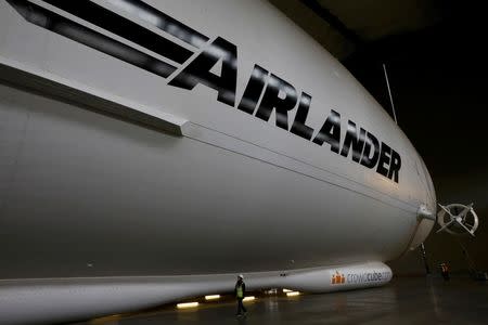 A worker walks alongside the Airlander 10 hybrid airship during its unveiling in Cardington, Britain March 21, 2016. REUTERS/Darren Staples