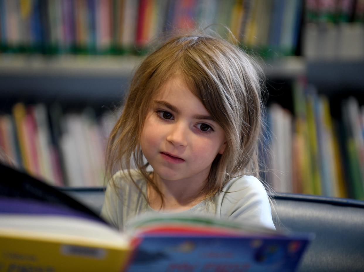 Adelaide King, 5, listens as her mother, Stephanie King of Munroe Falls reads her a story on a visit to North Canton Public Library.