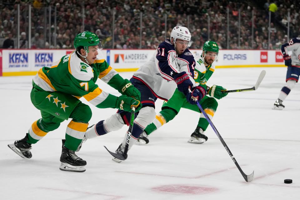 Columbus Blue Jackets center Adam Fantilli (11) battles for the puck against Minnesota Wild defenseman Brock Faber (7), left, and center Frederick Gaudreau (89), right, during the first period of an NHL hockey game Saturday, Oct. 21, 2023, in St. Paul, Minn. (AP Photo/Abbie Parr)