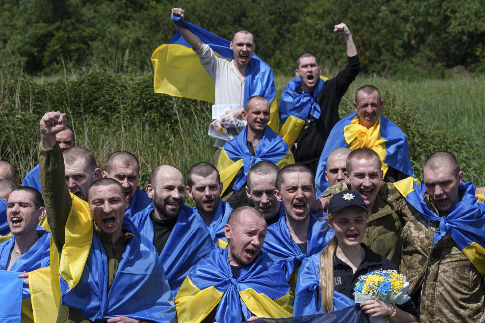 Ukrainian servicemen shout "Glory to Ukraine" after returning from captivity during POWs exchange in Sumy region, Ukraine, Friday, May 31, 2024. Ukraine returned 75 prisoners, including four civilians, in the latest exchange of POWs with Russia. It's the fourth prisoner swap this year, and 52nd since Russia invaded Ukraine. In all, 3 210 Ukrainian servicemen and civilians were returned since the outbreak of the war. (AP Photo/Evgeniy Maloletka)