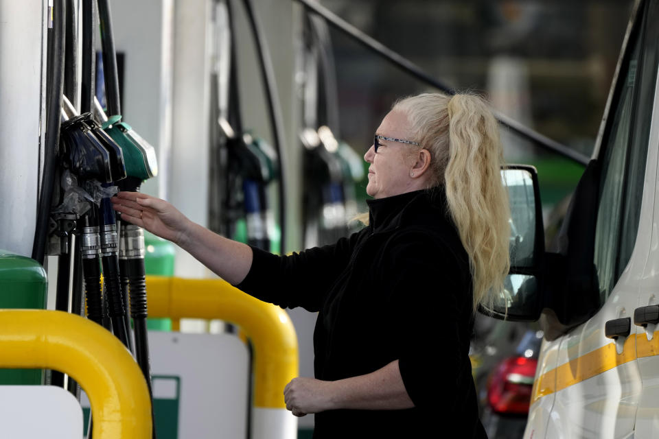A woman takes a petrol nozzle to fuel her car at a petrol station in London, Tuesday, March 8, 2022. Prices for petrol and diesel reached new highs due to Russia's war in Ukraine.(AP Photo/Frank Augstein)