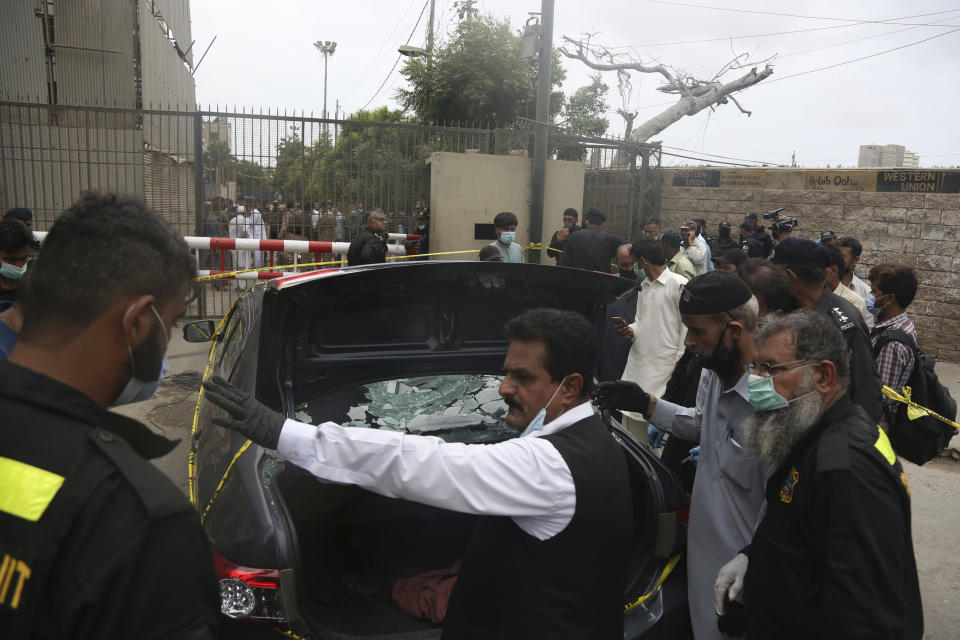 Security personnel check a car used by attackers at the Stock Exchange Building in Karachi, Pakistan, Monday, June 29, 2020. Gunmen attacked the stock exchange on Monday. Special police forces deployed to the scene of the attack and in a swift operation secured the building. (AP Photo/Fareed Khan)