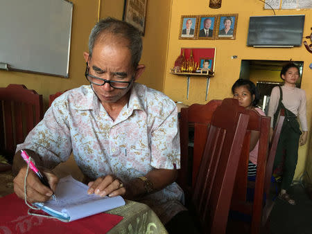 Bun Saroeun, writes a check at his restaurant at the Preah Sihanoukville province, Cambodia November 27, 2017. REUTERS/Matthew Tostevin