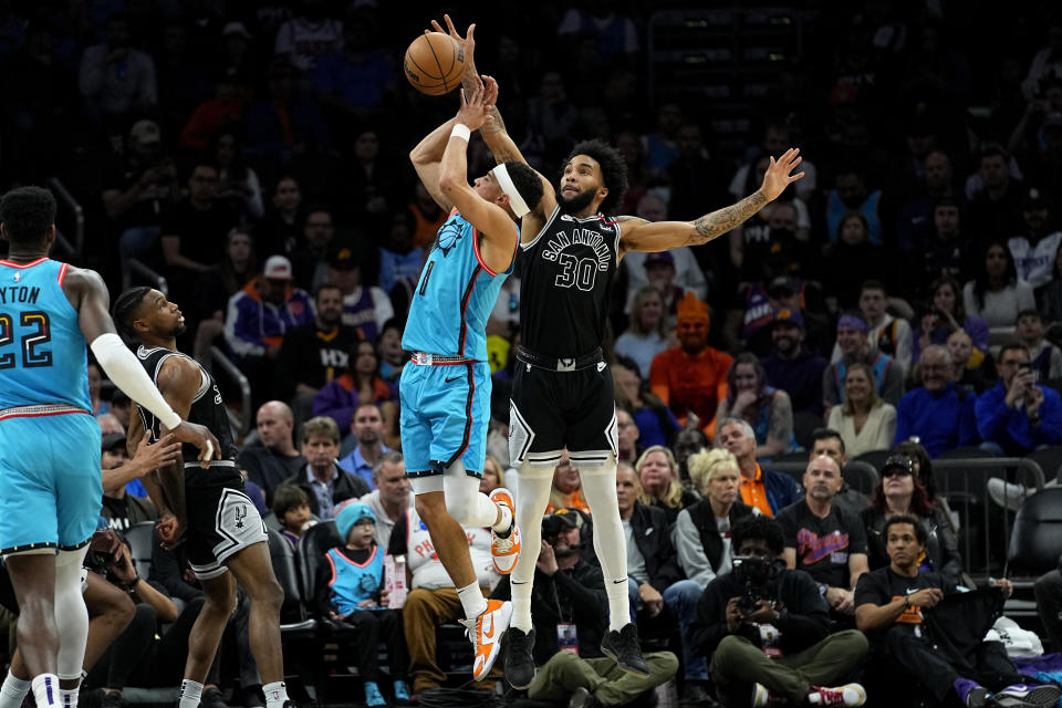 Phoenix Suns guard Devin Booker is fouled by San Antonio Spurs forward Julian Champagnie (30) during the first half of an NBA basketball game, Tuesday, April 4, 2023, in Phoenix. (AP Photo/Matt York)