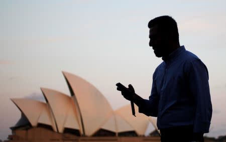 An office worker uses his mobile phone in front of the Sydney Opera House as he leaves Sydney's CBD September 26, 2012. REUTERS/Daniel Munoz