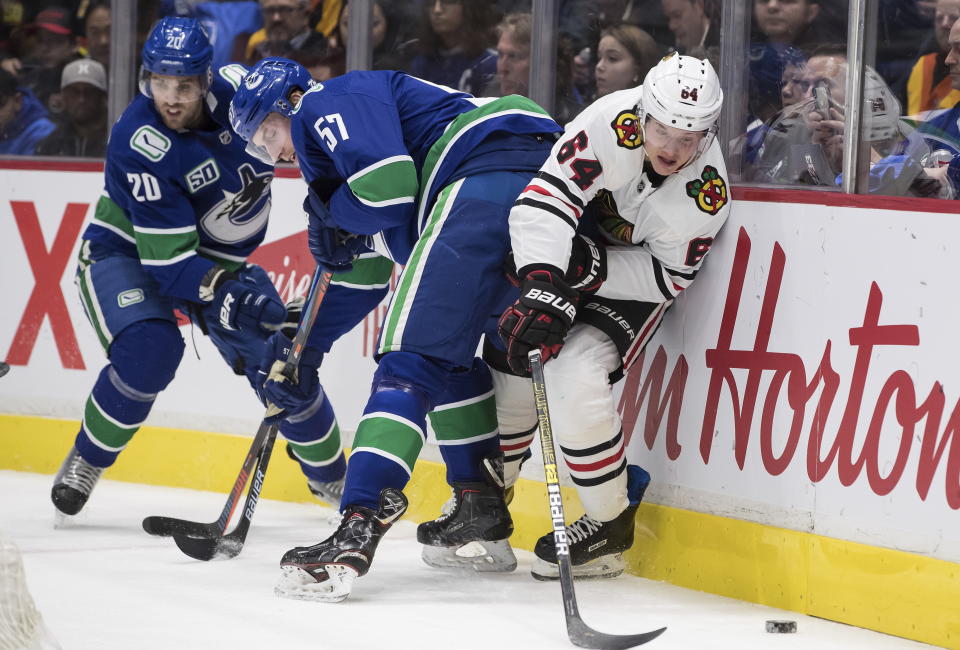 Vancouver Canucks' Tyler Myers (57) checks Chicago Blackhawks' David Kampf (64), of the Czech Republic, during the first period of an NHL hockey game Wednesday, Feb. 12, 2020, in Vancouver, British Columbia. (Darryl Dyck/The Canadian Press via AP)