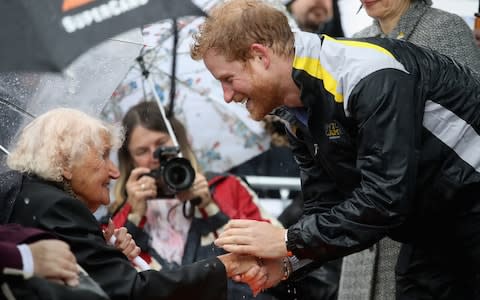 Prince Harry greets Daphne Dunne during a walkabout in the torrential rain ahead of a Sydney 2018 Invictus Games Launch Event, in June 2017  - Credit: Chris Jackson/Getty Images