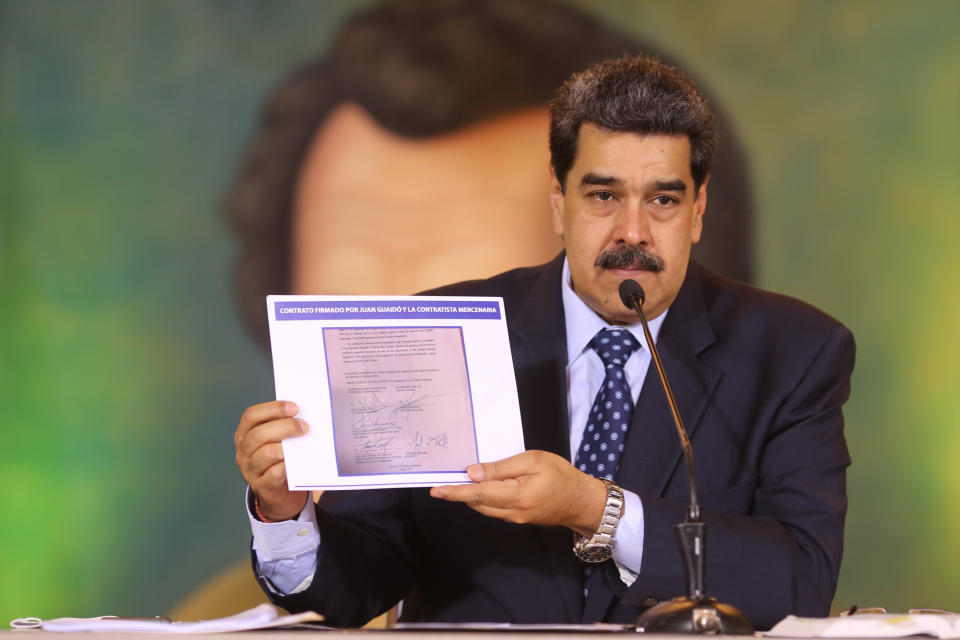 In this photo released by the Venezuela’s Miraflores presidential press office, President Nicolas Maduro accuses opposition leader Juan Guaido of being behind a military raid designed to oust him, as he holds a copy of a written agreement that allegedly bears Guaido’s signature as evidence, during an online press conference in Caracas, Venezuela, Wednesday, May 6, 2020. (Miraflores Palace presidential press office via AP)