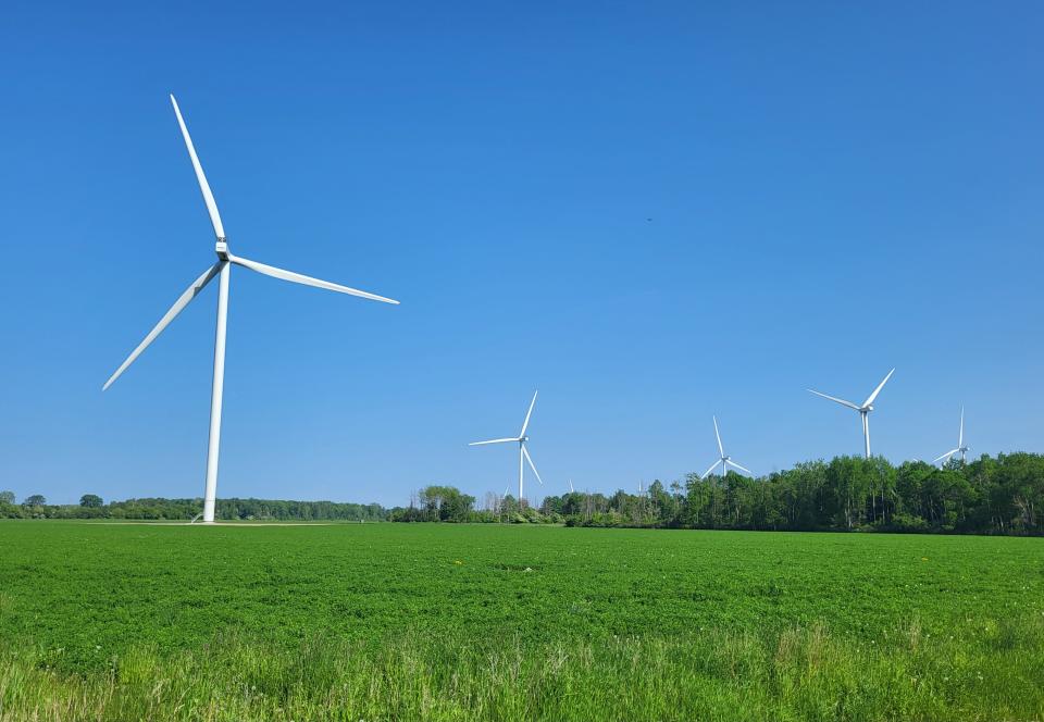 Wind turbines spin over a field in Huron Township on Tuesday, May 30, 2023.