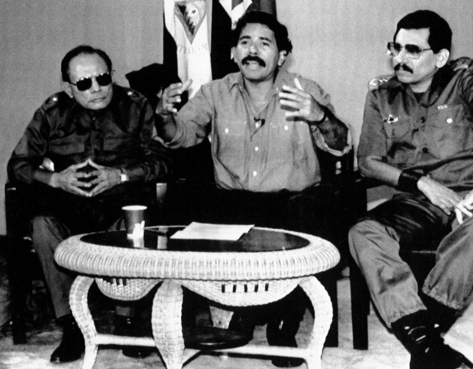 FILE - Nicaraguan Defense Minister Humberto Ortega, right, sits next to his brother, President Daniel Ortega, center, and Interior Minister Tomas Borge during an announcement of the expulsion of U.S. diplomats and the U.S. embassy's administrative and service workers in retaliation for an incident at the Nicaraguan embassy in Panama, Dec. 30, 1989. On Tuesday, May 21, 2024, Nicaraguan police announced Humberto Ortega was under watch, citing health reasons, hours after a controversial interview. (AP Photo/Ernest Mejia, File)