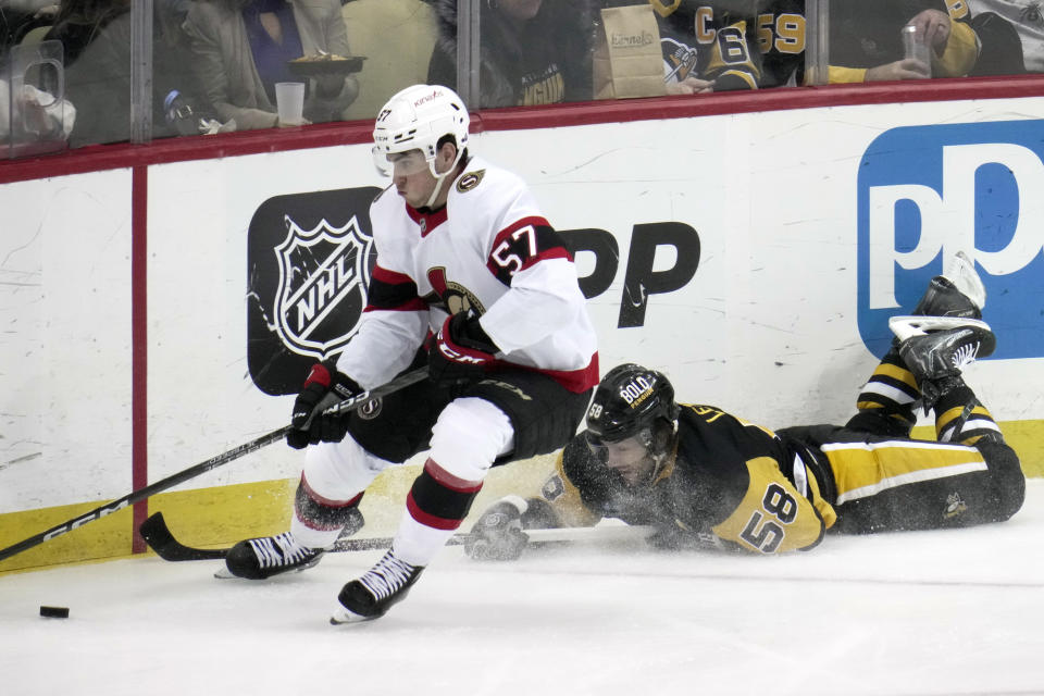 Ottawa Senators' Shane Pinto (57) works the puck with Pittsburgh Penguins' Kris Letang (58) defending on a power play during the second period of an NHL hockey game in Pittsburgh, Monday, March 20, 2023. (AP Photo/Gene J. Puskar)