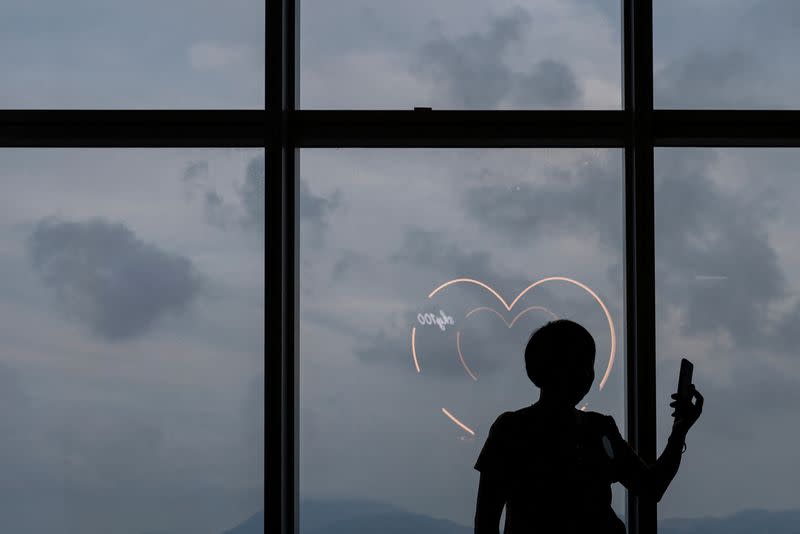 A woman takes a photo in front of heart-shaped light installations in Hong Kong