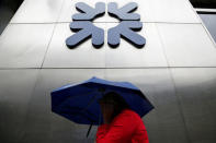 FILE PHOTO: A woman shelters under an umbrella as she walks past a branch of the Royal Bank of Scotland in the City of London, Britain, September 17, 2013. REUTERS/Stefan Wermuth/File Photo