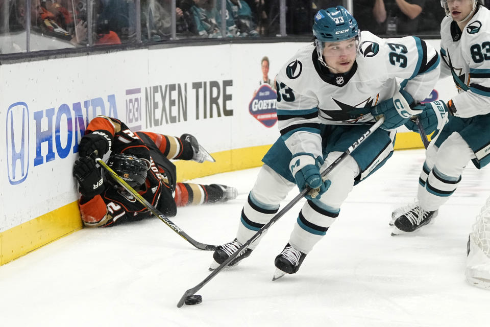 San Jose Sharks defenseman Calen Addison, right, takes the puck as Anaheim Ducks center Isac Lundestrom slides into the boards during the first period of an NHL hockey game Wednesday, Jan. 31, 2024, in Anaheim, Calif. (AP Photo/Mark J. Terrill)