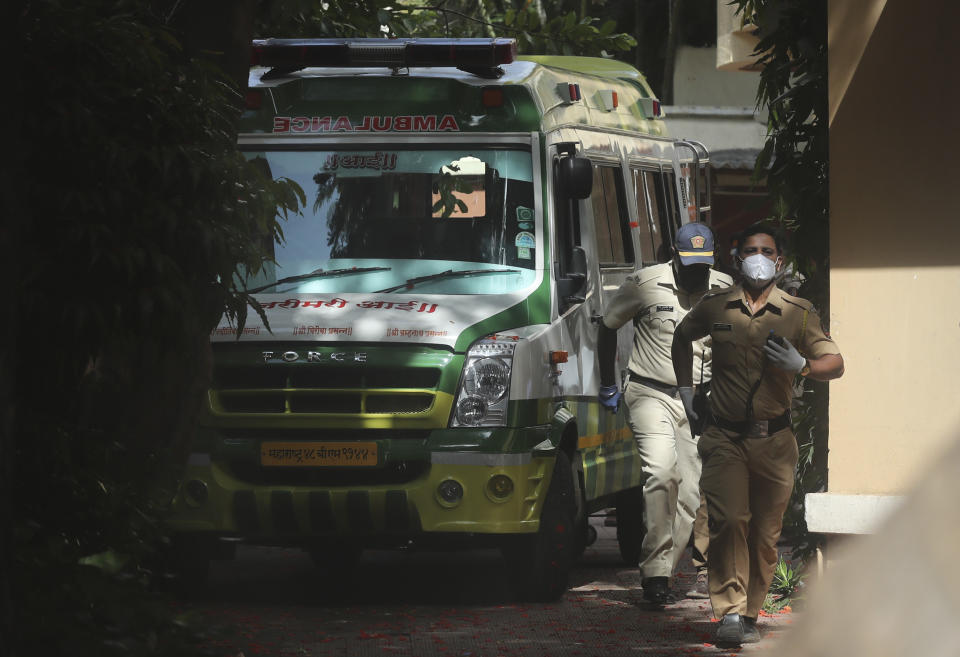 Policemen walk near an ambulance carrying the body of Bollywood actor Sushant Singh Rajput before it leaves from the building he lived in Mumbai, India, Sunday, June 14, 2020. The entertainment capital of India may be reeling under the coronavirus onslaught, but its celebrity inhabitants are being roiled by troubles of another kind. The recent suicide of Rajput, a young and popular movie actor in Mumbai has fueled a sustained reckoning over the privileges of the Bollywood elite, laying bare the simmering fault lines between the haves and the have-nots of the Hindi language movie industry. (AP Photo/Rafiq Maqbool,file)