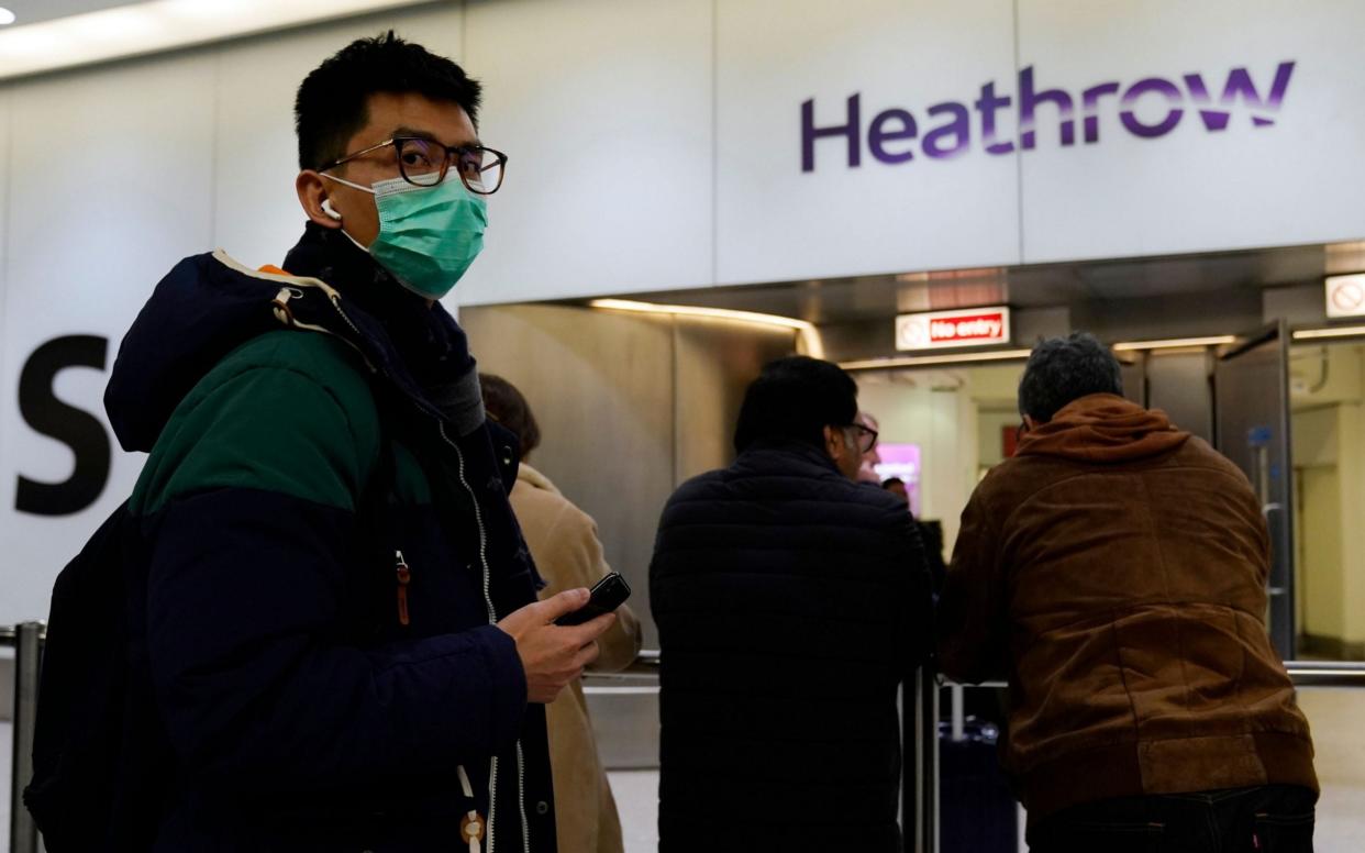 A passenger arrives wearing a mask at Terminal 4, Heathrow Airport - REX