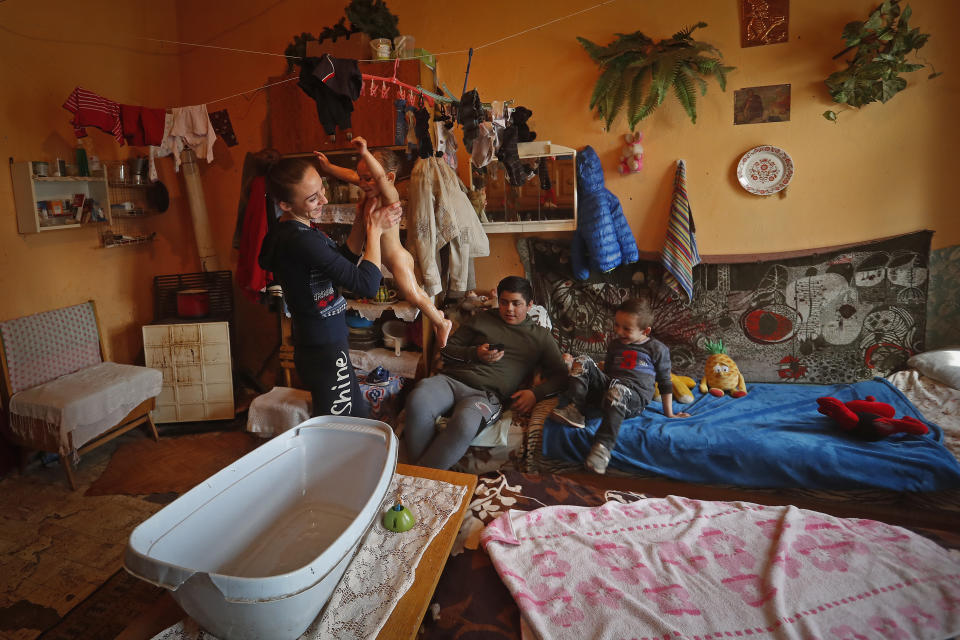 Karmen Bastyur, a 22 year old Hungarian Roma woman, lifts her daughter Fruzsina after giving her a bath in the family home which lacks running water in Bodvaszilas, Hungary, Monday, April 12,2021. Many students from Hungary's Roma minority do not have access to computers or the internet and are struggling to keep up with online education during the pandemic. Surveys show that less than half of Roma families in Hungary have cable and mobile internet and 13% have no internet at all. (AP Photo/Laszlo Balogh)