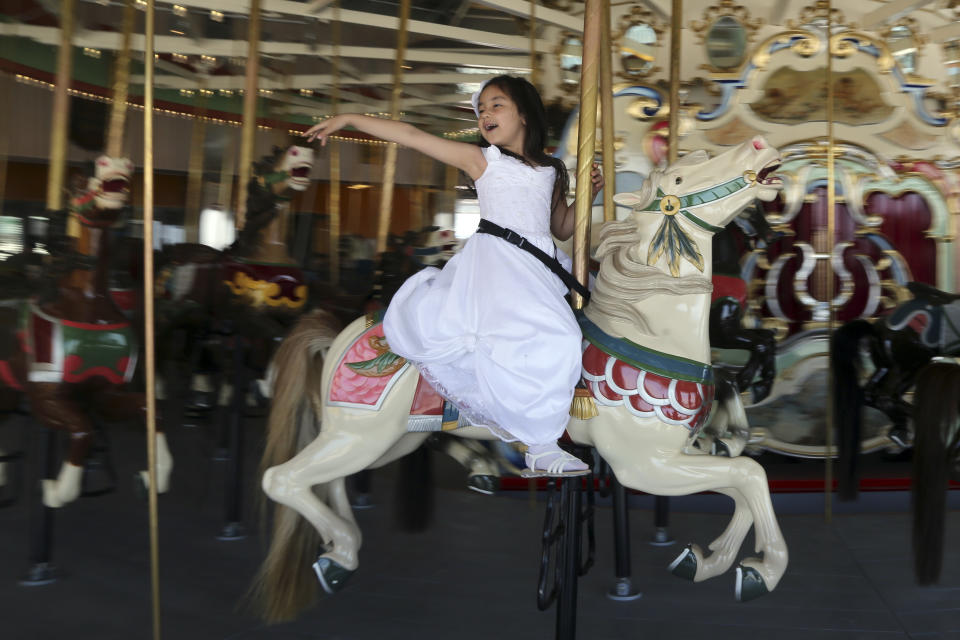 A child rides the B & B Carousel on the Coney Island's boardwalk, Wednesday, June 19, 2013 in New York. Eight months after Superstorm Sandy hit New York City, Coney Island's rides, eateries and beach are getting plenty of visitors, and there are even a few new attractions like a carousel and a store for fans of the Nets basketball team. (AP Photo/Mary Altaffer)