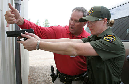 FILE PHOTO -- U.S. Border Patrol agent and instructor Salim Tourk (in red) helps trainee Mary Momberg, 31, with proper sighting techniques when using her Heckler & Koch .40 caliber P2000 handgun after a class session on the firing range at the U.S. Border Patrol Training Academy in Artesia, New Mexico, August 17, 2006. REUTERS/Jeff Topping/File Photo