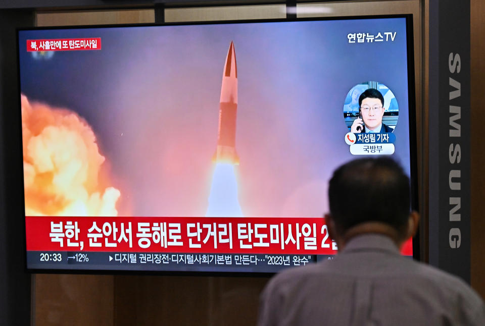 A man watches a television screen showing a news broadcast with file footage of a North Korean missile test, at a railway station in Seoul on September 28, 2022.