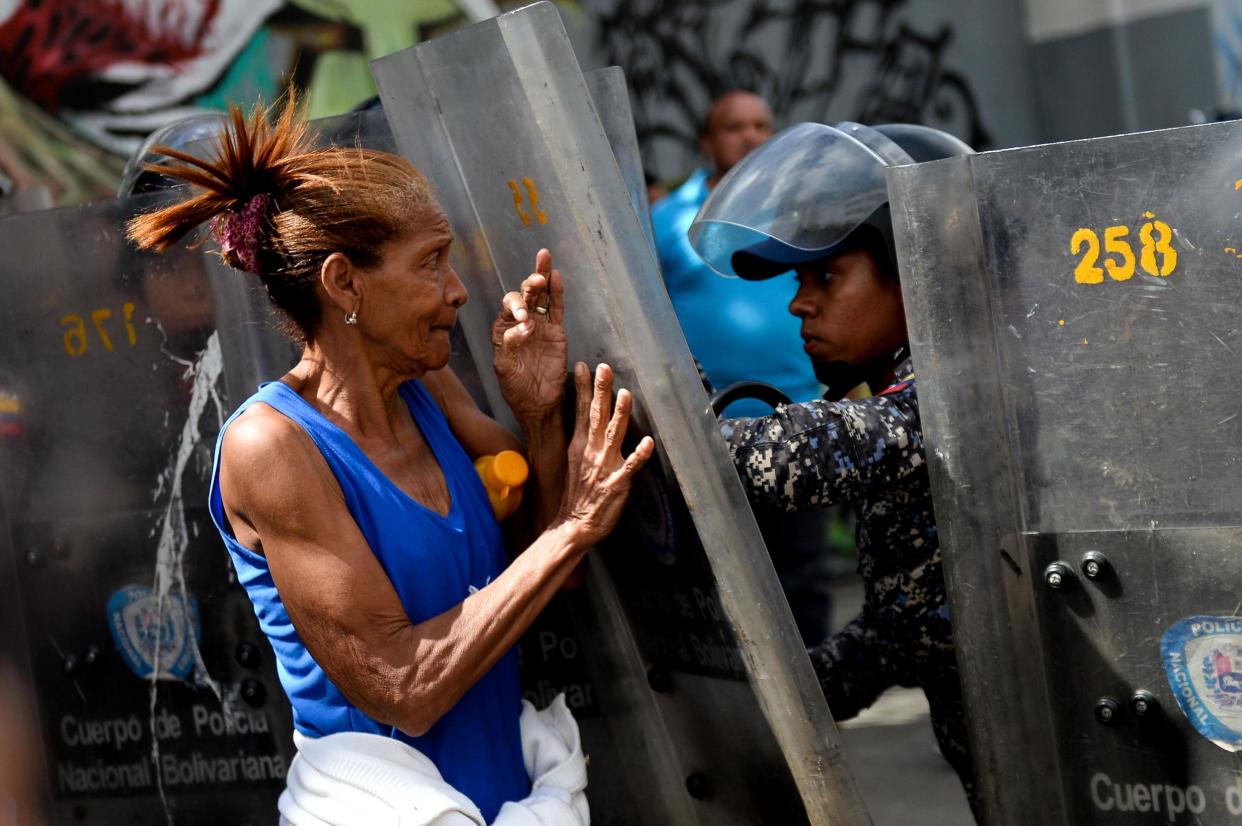 A Venezuelan woman confronts riot police during a protest against the shortage of food in Caracas on 28 December: AFP
