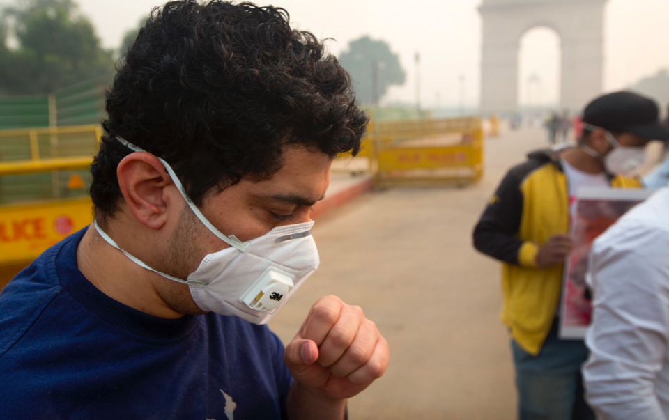 <em>An Indian coughs even after wearing a mask a day after Diwali festival (AP)</em>