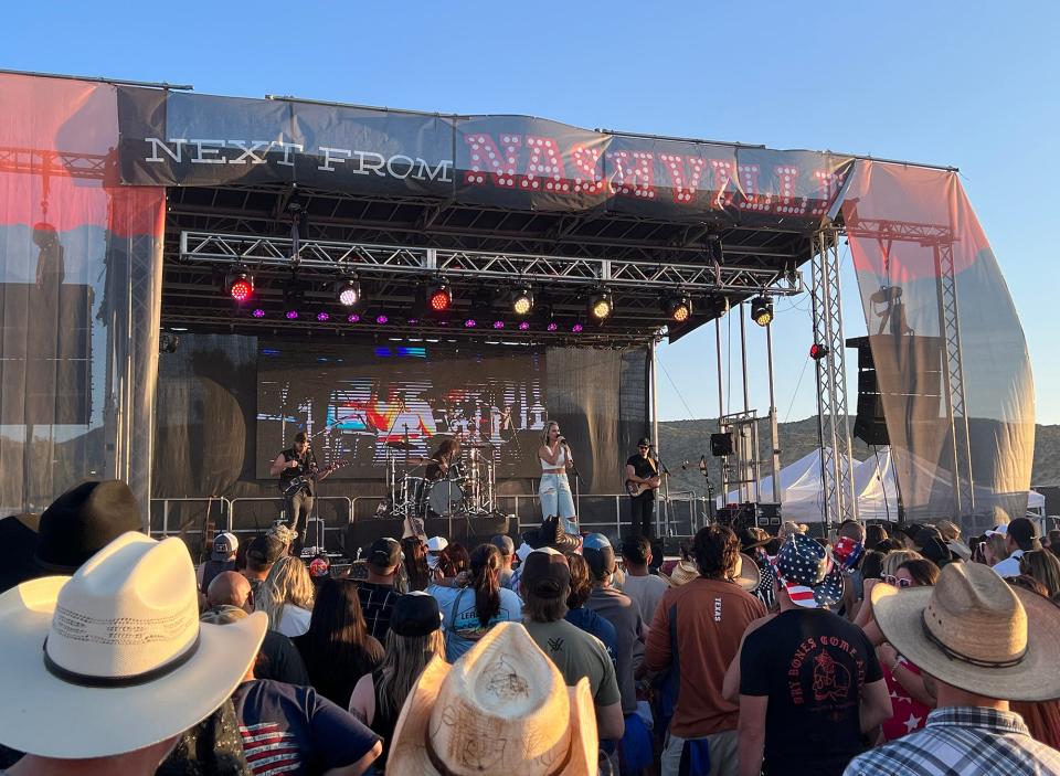 group of people wearing cowboy hats or no hats in front of a stage with ashley cooke performing on it