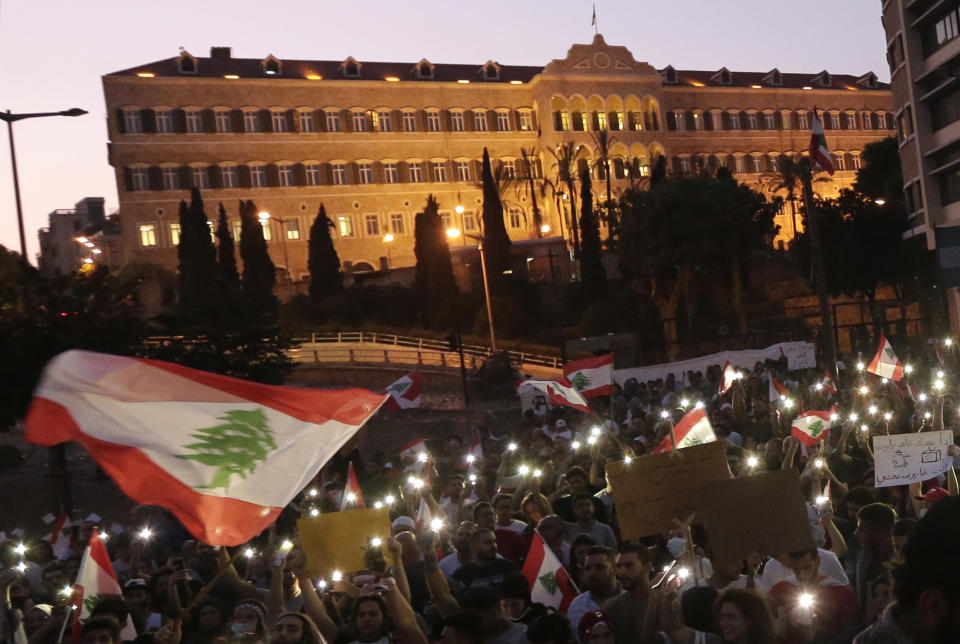 Anti-government protesters use the light on their phones and shout slogans against the Lebanese government during a protest in Beirut, Lebanon, Monday, Oct. 21, 2019. Lebanon's Cabinet approved Monday sweeping reforms that it hopes will appease thousands of people who have been protesting for five days, calling on Prime Minister Saad Hariri's government to resign. (AP Photo/Hassan Ammar)