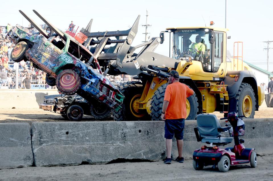 Craig Beaubien watches his car get lifted away from the track at the Monroe County Fair Demolition Derby.