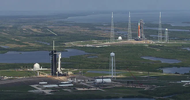 O Falcon 9 da SpaceX em primeiro plano na Plataforma de Lançamento 39A; SLS da NASA está em segundo plano na Plataforma de Lançamento 39B (Imagem: Reprodução/NASA/Jamie Peer)