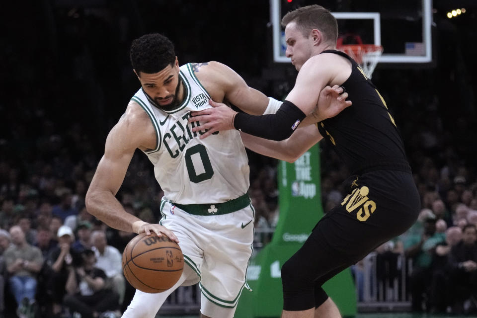 Boston Celtics forward Jayson Tatum (0) tries to break free from Cleveland Cavaliers guard Sam Merrill on a drive to the basket during the first half of Game 1 of an NBA basketball second-round playoff series Tuesday, May 7, 2024, in Boston. (AP Photo/Charles Krupa)