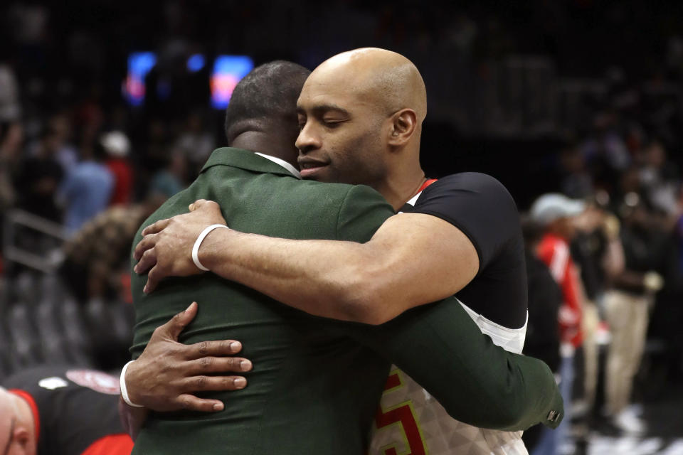 FILE - In this March 11, 2020, file photo, Atlanta Hawks guard Vince Carter, right, hugs former Hawk Dominique Wilkins as he leaves the court following an NBA basketball game against the New York Knicks in Atlanta. When the NBA announced the night of March 11 that it would be halting play because of the pandemic, word filtered through the arena and all the way down to the bench of the shocking developments. The fans began chanting for Carter to enter a game for the Hawks in the closing seconds. Carter had already announced it would be the final season of his brilliant 23-year career, longer than anyone else has played in the NBA. The fans sensed that the season might be over. The Hawks sent him back to the court. The Knicks respectfully backed away to give him an open look at a 3-pointer. (AP Photo/John Bazemore, File)