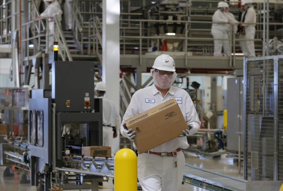 An associate carries a box of Snickers candy as production begins at the Mars Chocolate North America Topeka Plant near Topeka, Kan., Thursday, March 27, 2014. (AP Photo/Orlin Wagner)