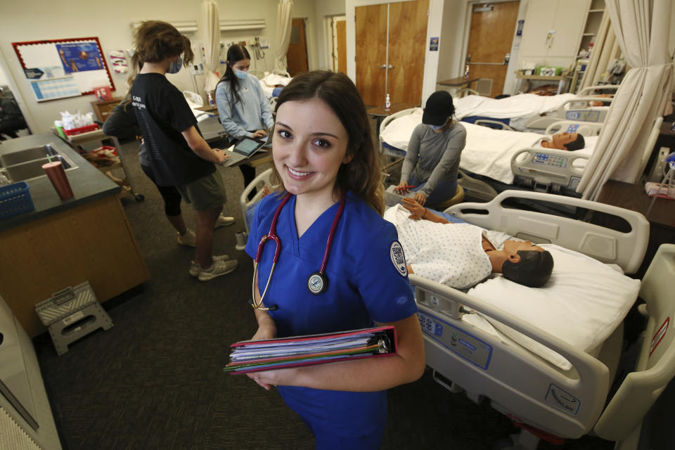 First year nursing student, Emma Champlin, poses for a photo in her clinical laboratory class at Fresno State on Wednesday, Oct. 13, 2021, in Fresno, Calif. Champlin said that like many of her classmates, she saw the pandemic as a chance to learn critical-care skills and to help at a time when those abilities are needed. (AP Photo/Gary Kazanjian)