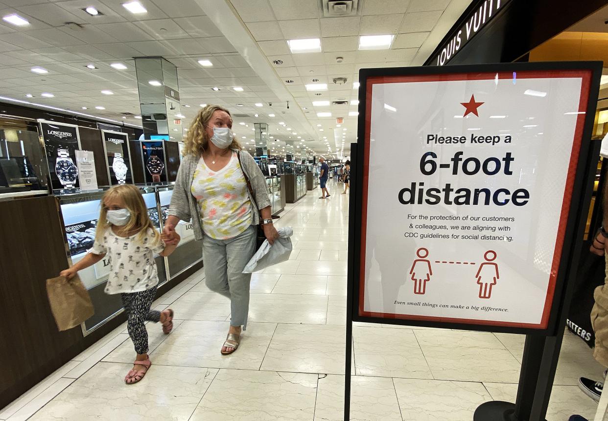 Customers walk past a sign that encourages people to keep a six foot distance from each other at Roosevelt Field Mall in Garden City, New York, which reopened on July 10, 2020. The openings follow Gov. Andrew M. Cuomo’s announcement on Wednesday that malls outside of New York City can open if they have high-efficiency air filtration systems to help control the spread of the virus.