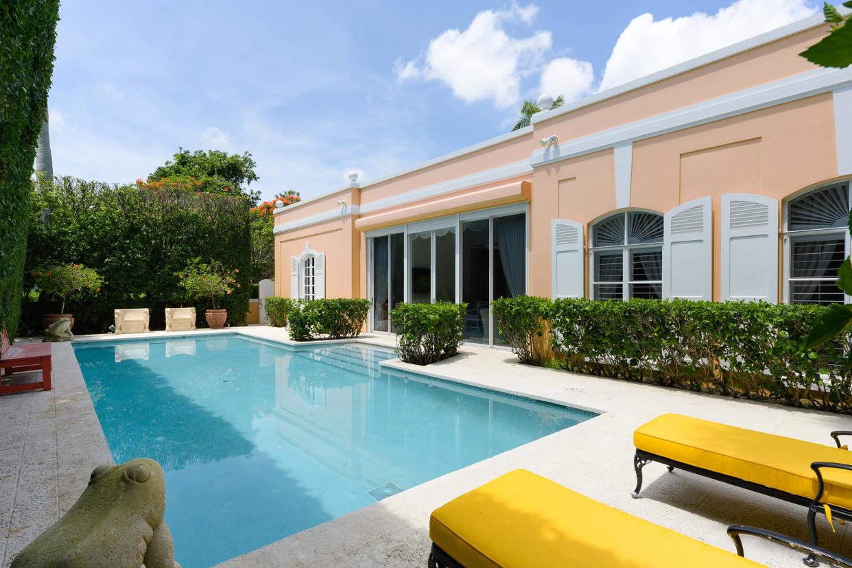 Glass doors and arched windows look out to the pool patio at 309 Chapel Hill Road in Palm Beach.