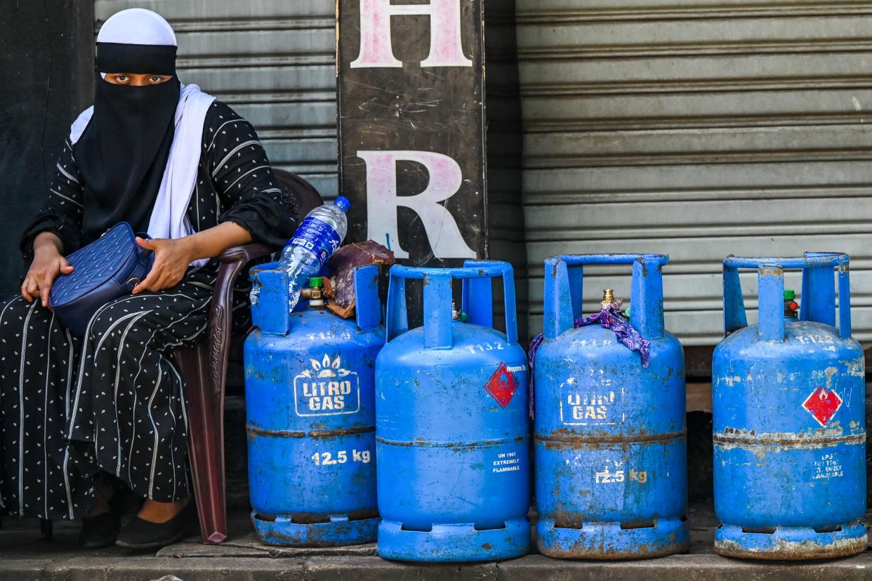 A woman sits beside Liquefied Petroleum Gas (LPG) cylinders along a street in Colombo, Sri Lanka on May 23, 2022. (Photo by Ishara S. KODIKARA / AFP) (Photo by ISHARA S. KODIKARA/AFP via Getty Images)