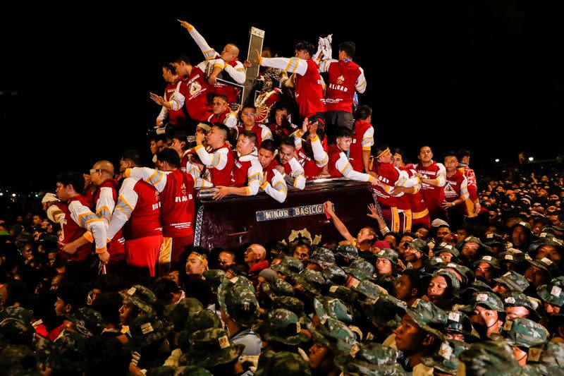 Filipino devotees join the annual Catholic procession of the Black Nazarene as police surround its carriage during its feast day in Manila