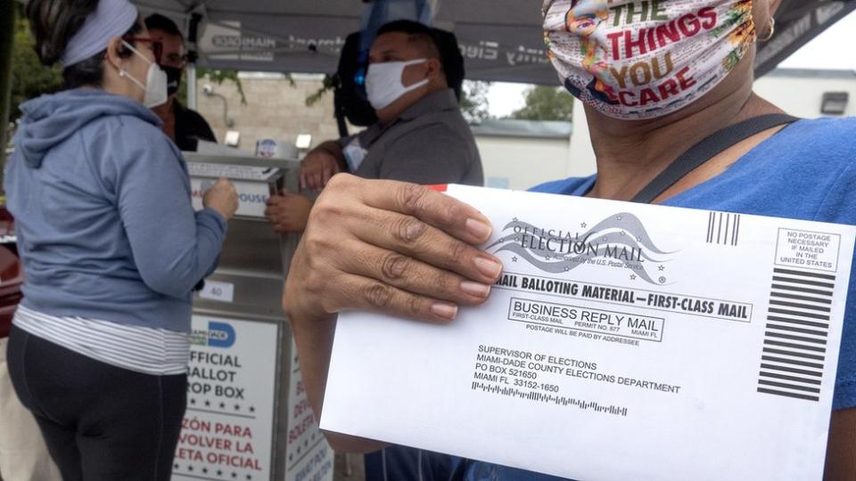 Una mujer con un sobre de votación en la mano