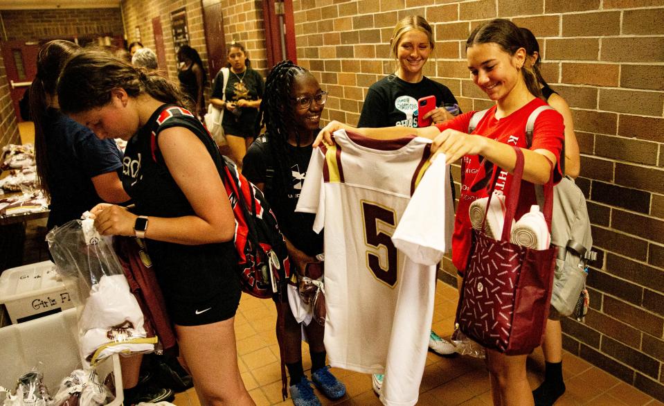 Ava Costello, center right, a member girls flag football team looks at her new jersey on Monday, Feb. 12, 2024. Flag football is a new sport in Lee County schools.