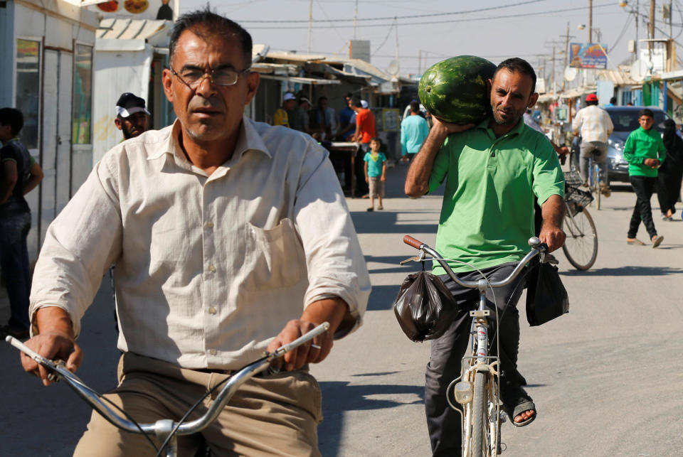 A Syrian refugee man carries a watermelon as he rides a bicycle on the main market at the Al-Zaatari refugee camp June 1.