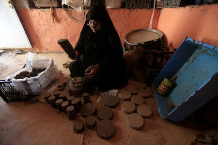 A woman makes ''turba'', a piece of stone or molded clay made of local soil, at her home in Kerbala, Iraq April 2, 2018. Picture taken April 2, 2018. REUTERS/Alaa Al-Marjani